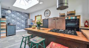 une cuisine avec un comptoir, une cuisinière et des tabourets dans l'établissement Grenville House, à Kilkhampton