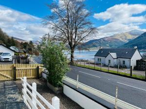 a white fence next to a road and a house at Avoca House in Fort William