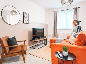 uma sala de estar com um sofá laranja e uma televisão em Templer Mill by Solace Stays 2 Shower Rooms em Newport