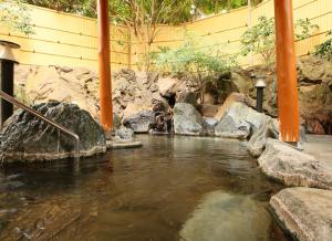 una corriente de agua con polos y rocas naranjas en Ito Kowakien en Ito