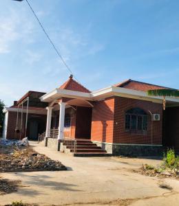 une maison en briques rouges avec une terrasse couverte et des marches. dans l'établissement HOSTEL ECO TOURISM CẦN GIỜ, à Cần Giờ