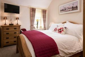 a bedroom with a bed with a red blanket on it at Dryburgh Stirling Two in Saint Boswells