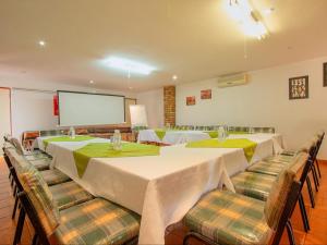 a conference room with tables and chairs and a screen at Airport Game Lodge in Kempton Park