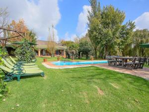 a yard with chairs and a swimming pool with a house at Airport Game Lodge in Kempton Park