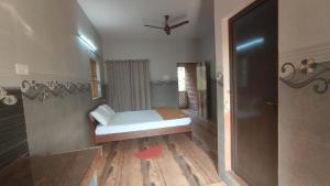 niewielka sypialnia z łóżkiem i wentylatorem sufitowym w obiekcie Dakshinamurthi Beach Stay w mieście Gokarna