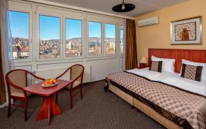ein Schlafzimmer mit einem Bett und einem Tisch mit einer Obstschale darauf in der Unterkunft Hotel Charles in Budapest