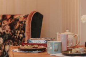 a table with plates and cups on top of it at The Garden Hut Cilcain in Mold