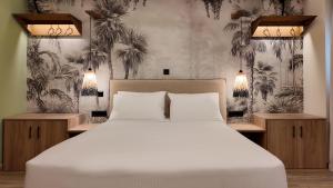 a bedroom with a white bed and palm trees wallpaper at Euphoria Apartments Monastiraki in Athens