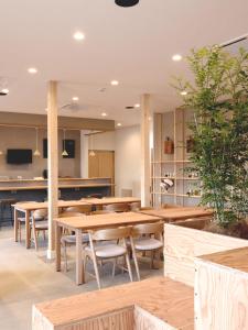 uma sala de jantar com mesas e cadeiras de madeira em Matoi Hostel & Bar em Takasaki