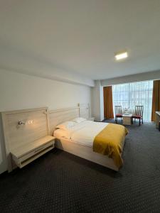Un dormitorio con una cama grande y una mesa con sillas. en Hotel Yaky Center, en Piteşti