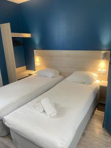 2 łóżka w pokoju z niebieskimi ścianami w obiekcie Kyriad Direct Dreux w mieście Dreux