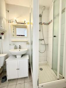 ein weißes Bad mit einem Waschbecken und einer Dusche in der Unterkunft Joli appartement cosy – Terrasse face à la mer in Ploemeur