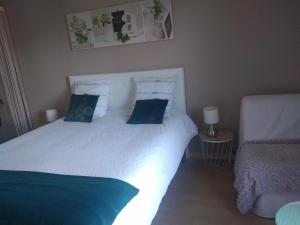 a bedroom with a large white bed with blue pillows at Chez Bernard et Nicole in Betton