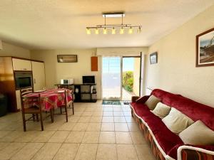 ein Wohnzimmer mit einem roten Sofa und einem Tisch in der Unterkunft Joli appartement cosy – Terrasse face à la mer in Ploemeur
