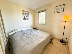 ein Schlafzimmer mit einem Bett, einer Lampe und einem Fenster in der Unterkunft Joli appartement cosy – Terrasse face à la mer in Ploemeur