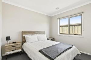 Habitación blanca con cama y ventana en Brand new House close to shops in Dunes estate en Torquay