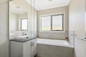 y baño con bañera y lavamanos. en Brand new House close to shops in Dunes estate en Torquay
