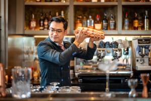 a man standing behind a bar holding a tray of food at InterContinental Chiang Mai The Mae Ping, an IHG Hotel in Chiang Mai