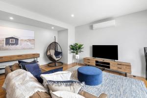ein Wohnzimmer mit einem Sofa und einem Flachbild-TV in der Unterkunft Brand New Townhouse Coastal Lifestyle Torquay in Torquay