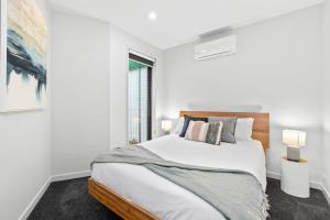 ein weißes Schlafzimmer mit einem großen Bett und einem Fenster in der Unterkunft Brand New Townhouse Coastal Lifestyle Torquay in Torquay