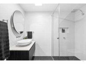 ein weißes Badezimmer mit Waschbecken und Spiegel in der Unterkunft Surf Central Townhouse - Walk to Beach and Shops in Torquay + 10 Fotos