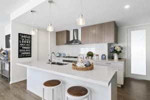 a white kitchen with a large island with two stools at Hampton's Getaway in Torquay in Torquay