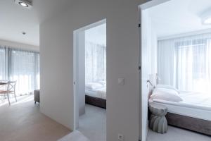 a white bedroom with a bed and a mirror at HEVENIA POGORZELICA - APARTAMENT 2 in Pogorzelica