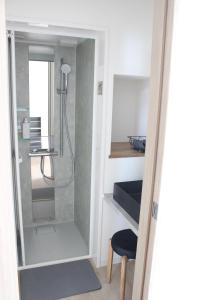 a bathroom with a shower and a stool and a mirror at Matoi Hostel & Bar in Takasaki