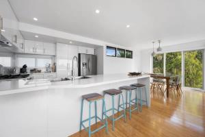 a kitchen with a white counter and bar stools at Panoramic Ocean Views in the Heart of Torquay in Torquay +16 photos