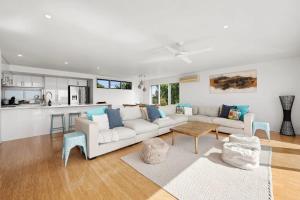 a living room with a white couch and a kitchen at Panoramic Ocean Views in the Heart of Torquay in Torquay