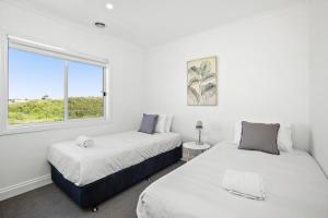2 bedden in een witte kamer met een raam bij Seaspray Ocean View Retreat in Torquay