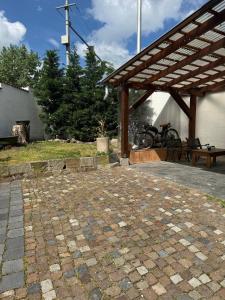 a stone patio with a wooden pergola and a bench at Pelini - 2 in Szentendre