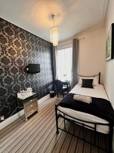a bedroom with a bed and a desk and a tv at Bamboo Guesthouse in Bournemouth