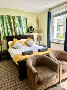 a bedroom with a large bed with two chairs at Bamboo Guesthouse in Bournemouth