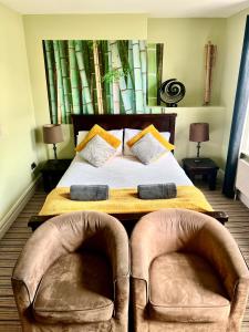 a bedroom with a large bed with two chairs at Bamboo Guesthouse in Bournemouth
