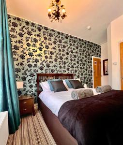 1 dormitorio con 1 cama y papel pintado con motivos florales en Bamboo Guesthouse en Bournemouth