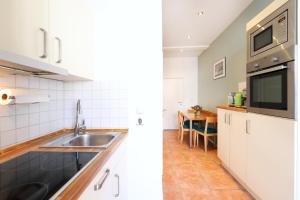 cocina con armarios blancos, fregadero y mesa en Appartementhaus Strandnähe, en Warnemünde
