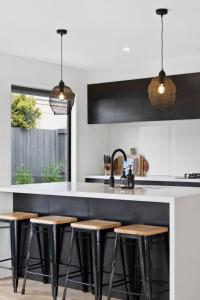 a kitchen with black and white counter tops and stools at Poolside near Beach and Shops in Torquay