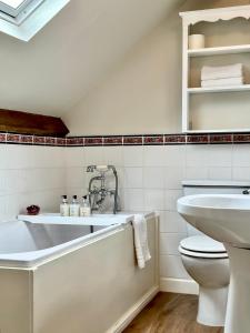 a white bathroom with a tub and a toilet at Broom House at Egton Bridge in Egton
