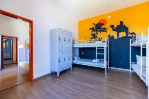 a room with three bunk beds and a yellow wall at The Macarena Beach Hostel in Lagos