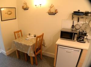 eine kleine Küche mit einem Tisch und einer Mikrowelle in der Unterkunft Seaview at Merton Hall Dinas Cross in Dinas
