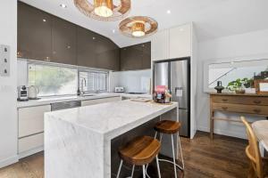 a kitchen with a large marble counter and stools at Whitewash Beachfront Apartment on The Esplanade in Torquay