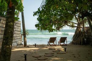 two chairs sitting on a beach near the ocean at Ocean front cabin in Madiha in Kamburugamuwa