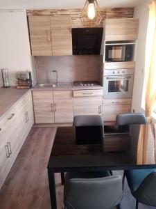 eine Küche mit Holzschränken und einem Tisch mit Stühlen in der Unterkunft Appartement centre ville in Vimoutiers