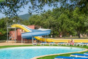 uno scivolo d'acqua in una piscina con persone sedute su sedie di Camping Acqua E Sole a Sainte-Lucie de Porto-Vecchio