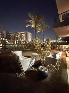 a patio with two chairs and a table and palm trees at Aura Apartments CFC in Cairo