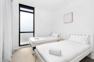 Duas camas num quarto com uma janela em Urban Executive Style Meets Relaxed Coastal Vibes em Ocean Grove