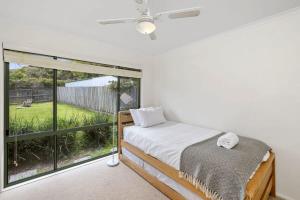a bedroom with a bed and a large window at Jan Juc Ocean Views And Sunshine in Torquay