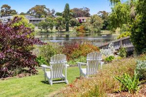two white chairs sitting in the grass near a lake at Bellarine Lake House Ocean Grove in Ocean Grove +20 photos
