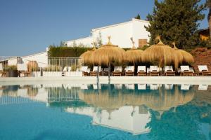 a pool with some straw umbrellas and chairs and some water at Inmood Aucanada 4 Sup in Port d'Alcudia